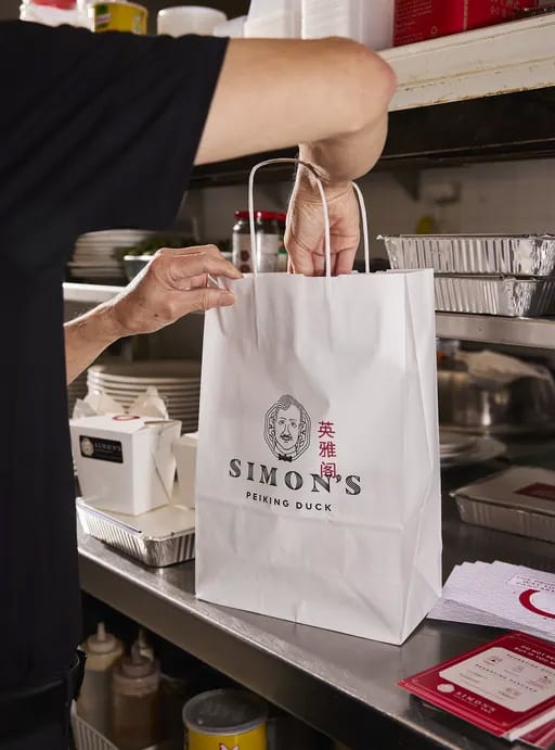 A person packs a custom takeaway bag